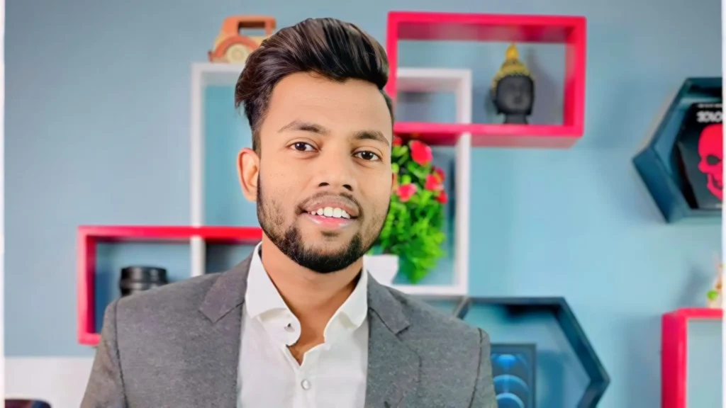 Manoj Dey , white teeth, grey coat , blue background